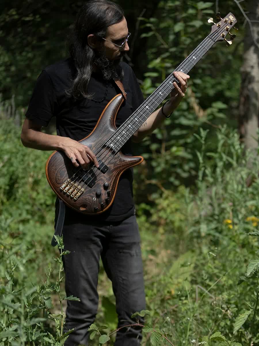Baixista de pé tocando, corpo inteiro.
