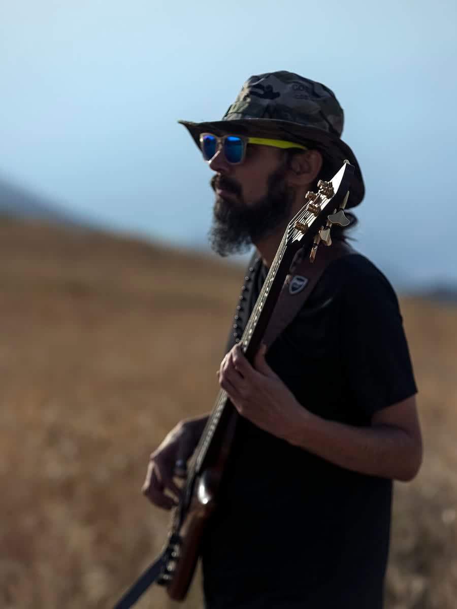 Baixista tocando ao ar livre, perfil.