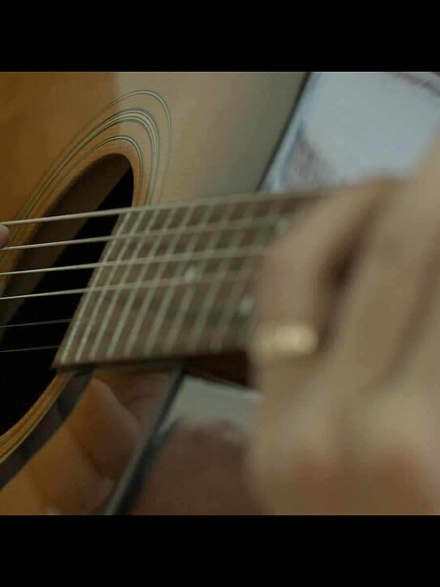 Mão direita dedilhando as cordas do violão.